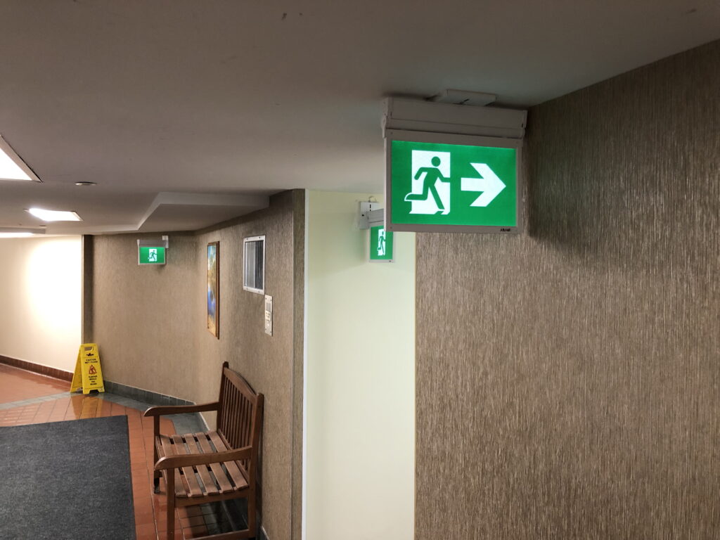 This image highlights a fire safety concern regarding the placement of an exit sign. Issues Identified:
Exit Sign Points Toward a Wall The sign directs people toward a solid wall instead of a clear exit path.
This could cause confusion in an emergency and slow evacuation efforts.
Code Compliance Concern Fire and building codes (such as NFPA 101 - Life Safety Code) require exit signs to accurately indicate the correct path to egress.
Misleading signage can violate fire safety regulations and lead to liability issues.
Recommended Actions:
✔ Verify the correct exit route and reposition the sign to accurately reflect the escape path.
✔ Conduct a fire safety audit to ensure all exit signs are properly installed and visible.
✔ Remove or replace conflicting signs that could mislead building occupants.
✔ Ensure compliance with fire codes by consulting local fire authorities or safety inspectors. This issue should be corrected immediately to prevent confusion during an emergency.