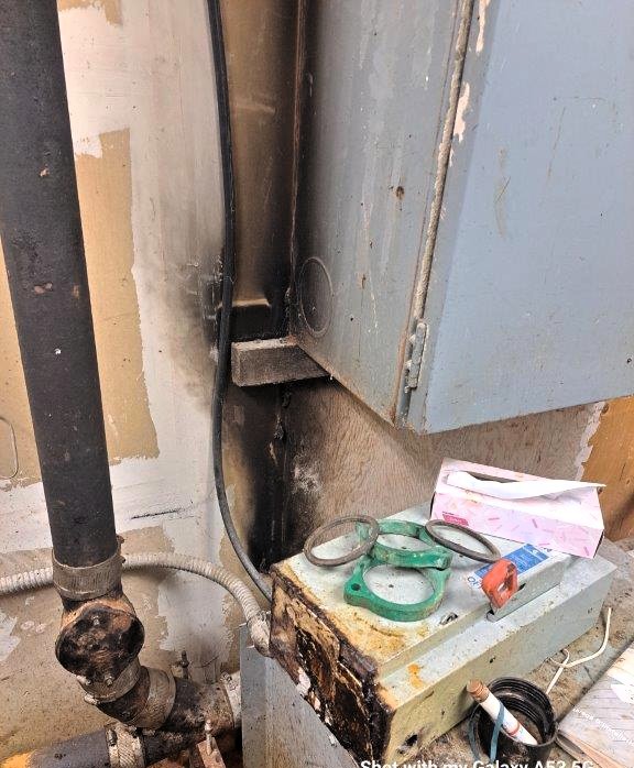 This image highlights a fire damage pattern near an electrical panel, presenting a significant fire safety concern.
Fire Protection Observations
1. V-Shaped Burn Pattern
o The visible V-pattern on the wall suggests a localized heat source at the base, which spread upward, indicating possible electrical ignition from the panel or nearby wiring.
o Fire investigators often analyze burn patterns to determine the fire's point of origin, and this suggests overheating or electrical arcing as potential causes.
2. Electrical Fire Risk
o The electrical panel and conduit show heat damage and scorching, which could result from faulty wiring, overloaded circuits, or a short circuit.
o If not promptly addressed, this poses a high risk of recurring electrical fires, jeopardizing building safety.
3. Improper Storage & Fire Load
o Items placed near the electrical panel, including gaskets, tools, and paper materials, increase fire risk by adding combustible fuel to the area.
o The Ontario Electrical Code requires clearances around electrical panels to prevent obstruction and reduce fire hazards.
Recommendations for Fire Safety Compliance
✔ Immediate inspection by a licensed electrician to assess wiring, connections, and any overheating components.
✔ Verify panel compliance with the Ontario Electrical Code to ensure proper installation and electrical safety measures.
✔ Remove combustible materials from the area and maintain a minimum clearance of 36 inches around the panel per code requirements.
✔ Investigate potential moisture intrusion or corrosion, which can cause electrical faults leading to arcing and fire.
This fire damage evidence requires urgent attention, as electrical fires can spread rapidly and cause extensive damage if left unaddressed.
