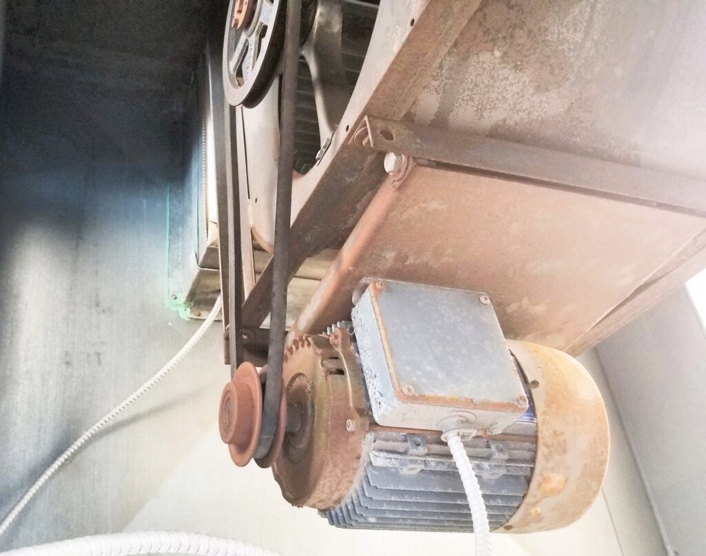 The image shows a pressurization fan with visible rust, corrosion, and dust buildup on its components, including the motor, belts, and pulley system. This could indicate poor maintenance, which may impact the fan’s efficiency and reliability. Pressurization fans are crucial for maintaining proper air circulation and preventing smoke migration in stairwells and other critical areas during a fire. Lack of maintenance could lead to operational failure, reducing their effectiveness in an emergency. It would be advisable to inspect, clean, and service the fan to ensure it functions properly and meets safety standards.